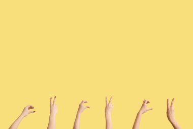 Sarı arka planda barış ve kalp hareketleri gösteren kadın elleri