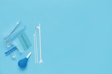 Pap smear test araçları ile jinekolojik spekulum ve mavi arka planda lavman