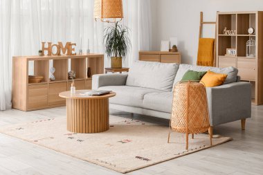 Gri kanepesi, ahşap masası ve lambaları olan rahat bir oturma odası.