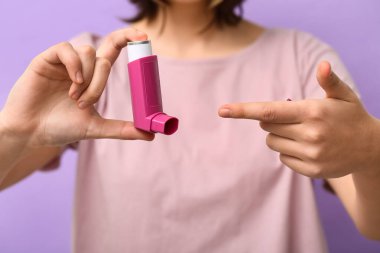 Leylak arka planında astım spreyi olan çocuk, yakın plan.