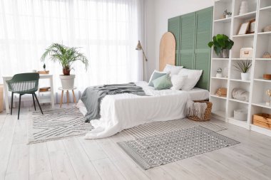 Yatak odasının içinde raf ünitesi, bitki ve lamba var.