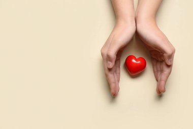 Bej arka planda kırmızı kalpli kadın elleri