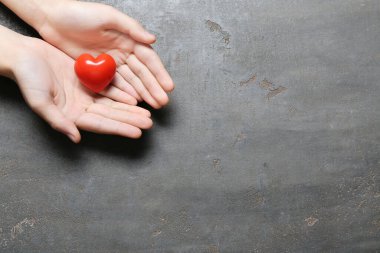 Siyah arka planda kırmızı kalpli kadın elleri