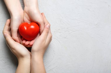 Beyaz arka planda kırmızı kalpli kadın ve çocuğun elleri