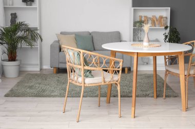 Masası, koltukları, rahat koltuğu, çiçekleri ve raf ünitesi olan rahat bir oturma odası.