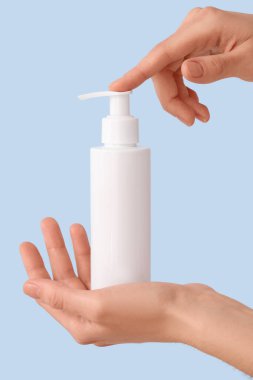 Renkli arka planda krem şişesi olan kadın elleri, yakın plan.