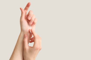 Ellerine krem süren kadın arka planda ışığa karşı, yakın plan