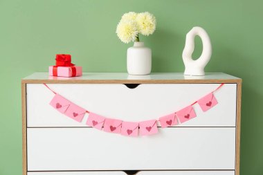 Oturma odasındaki beyaz çekmecelere asılmış kalpler, yakın plan. Sevgililer Günü kutlaması