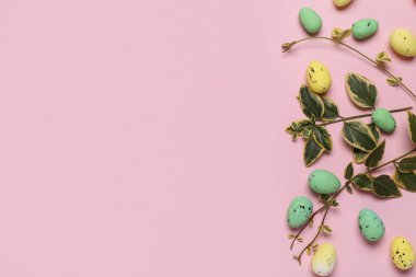 Pembe arka planda yaprakları olan Paskalya yumurtaları