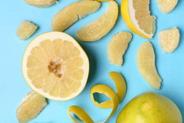 Lezzetli dilimlenmiş pomelo meyvesi ve mavi arka planda kabuk.
