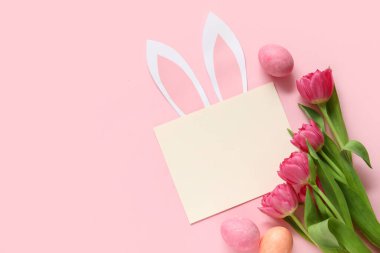 Yaratıcı kompozisyon, boş kart, laleler ve pembe arka planda yumurta. Paskalya kutlaması