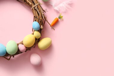 Güzel Paskalya çelengi boyalı yumurtalar ve pembe arka planda tüyler