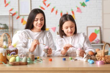 Küçük kız ve annesi mutfakta Paskalya yumurtası boyuyor.