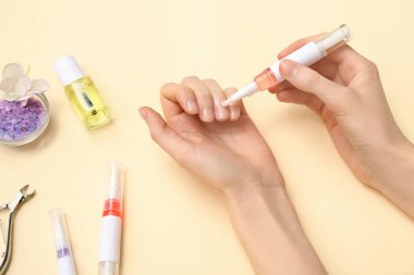 Bej arka planda tırnak eti yağı kalem ve deniz tuzu tutan kadın eller.