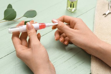 Tırnaklarına okaliptüs dalı ve yeşil ahşap arka planda havlu süren kadın elleri.