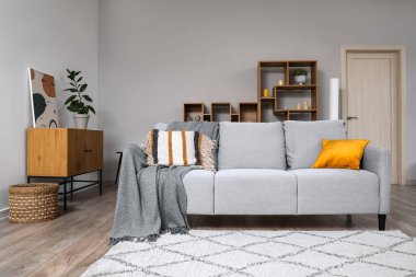 Oturma odasında yerde yastık ve halı olan rahat gri bir kanepe.