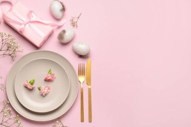 Şirin Paskalya sofrası, pembe arka planda hediyeler, çiçekler ve yumurtalar.