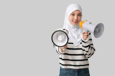 Gri arka planda megafonları olan genç Asyalı Müslüman kadın. Ulusal Duyulma Günü