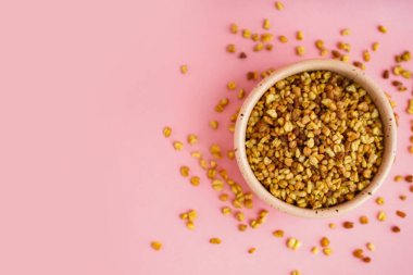 Pembe arka planda çiğ karabuğday taneleri olan kase