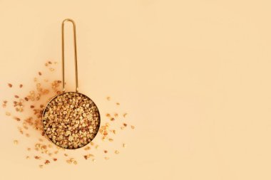 Bej arka planda çiğ karabuğday taneleriyle metal kepçesi