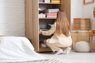 Genç bir kadın, temiz giysileri dolaba katlıyor.