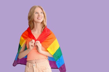 Mor arka planda LGBT bayrağı olan güzel, genç ve mutlu bir kadın.
