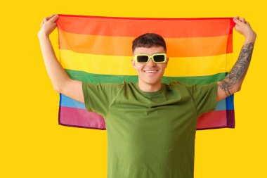 Sarı arka planda LGBT bayrağı olan yakışıklı genç adam.