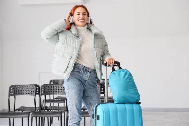 Havaalanında kulaklıklı ve çantalı kadın turist.