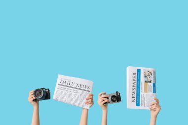 Renkli arka planda gazete ve fotoğraf makinesi olan kadın eller