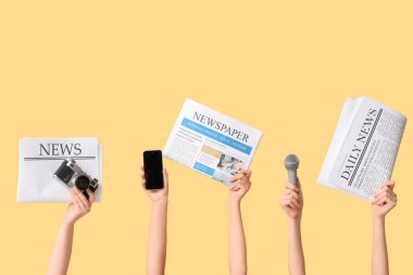 Sarı arka planda gazeteleri ve aletleri olan kadın eller.