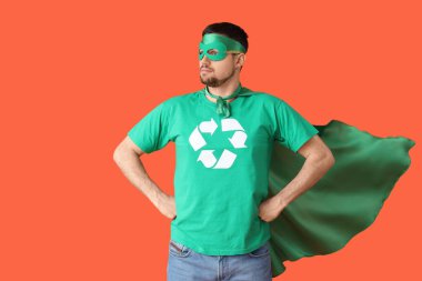 Turuncu arka planda çevreci süper kahraman gibi giyinmiş genç bir adam. Ekoloji kavramı