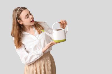 Gri arka planda sulama tenekesi olan güzel genç bir kadın.