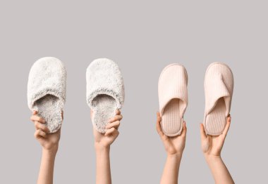 Beyaz arka planda terlikleri tutan kadın eller.