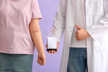 Kan torbası olan donör ve doktor leylak arka planında parmak izi gösteriyor. Yakın plan.