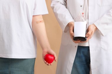 Bej arka planda kan torbası tutan kalp ve doktor donörü.