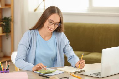 Hesap makineli kadın öğretmen evde online matematik dersi veriyor.