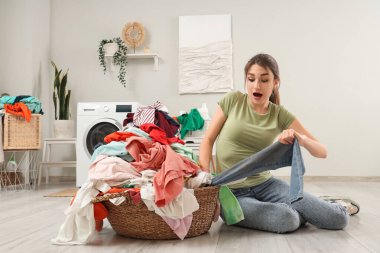 Çamaşır sepetiyle evde oturan genç bir kadın şok oldu.