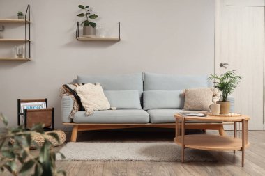 Gri kanepe, masa ve raflarla aydınlık oturma odasının içinde.