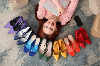 Genç bir kadın dizüstü bilgisayarı ve cep telefonu ile yerde yatıyor.