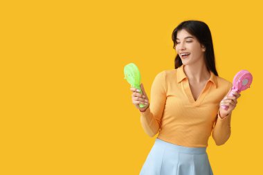 Sarı arka planda mini fanları olan genç bir kadın.