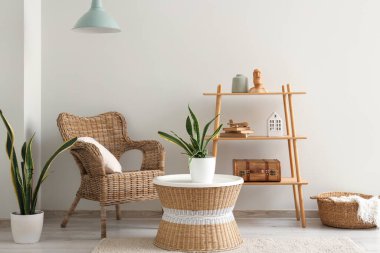 Hasır koltuğu, sehpası ve çiçekleri olan şık bir oturma odası.