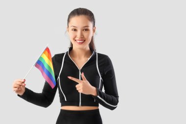 Hafif arkaplanda LGBT bayrağını gösteren Asyalı bayan sporcu