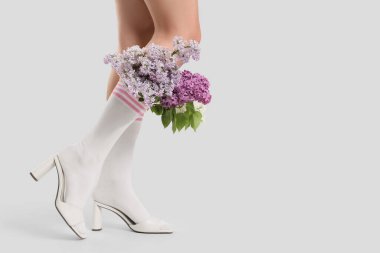 Açık arkaplanda çoraplı leylak çiçekli kadın.