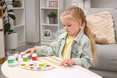 Evdeki tabloları ve fırçaları olan sevimli küçük bir kız.