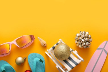 Mini plaj aksesuarları, gözlükleri ve renk arkaplanı üzerine Noel süslemeleri olan kompozisyon