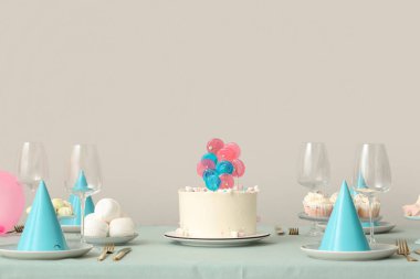 Doğum günü partisi için şekerli pasta ve tabaklar beyaz duvara karşı masada.