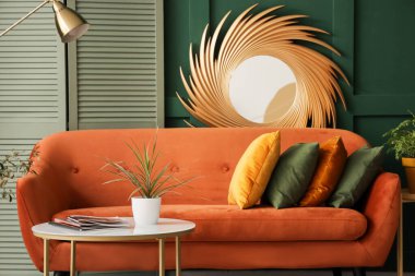 Yastıklı rahat bir kanepe, dergisi olan bir sehpa ve oturma odasında bitki.