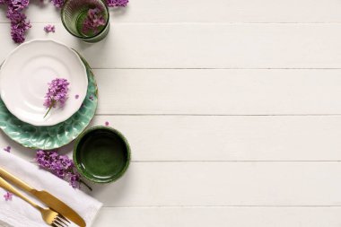 Beyaz ahşap arka planda leylak çiçekleri olan güzel bir masa.