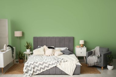 Yatağı, komodinleri, koltuğu ve lambası olan modern yatak odası.