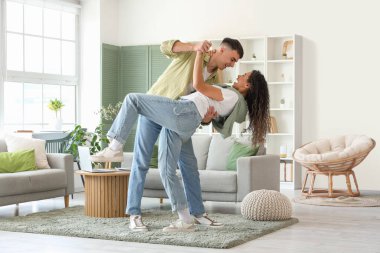 Happy young beautiful couple dancing at home